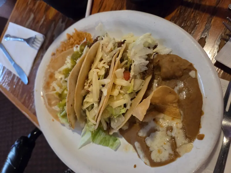 Three crispy tacos with rice and beans